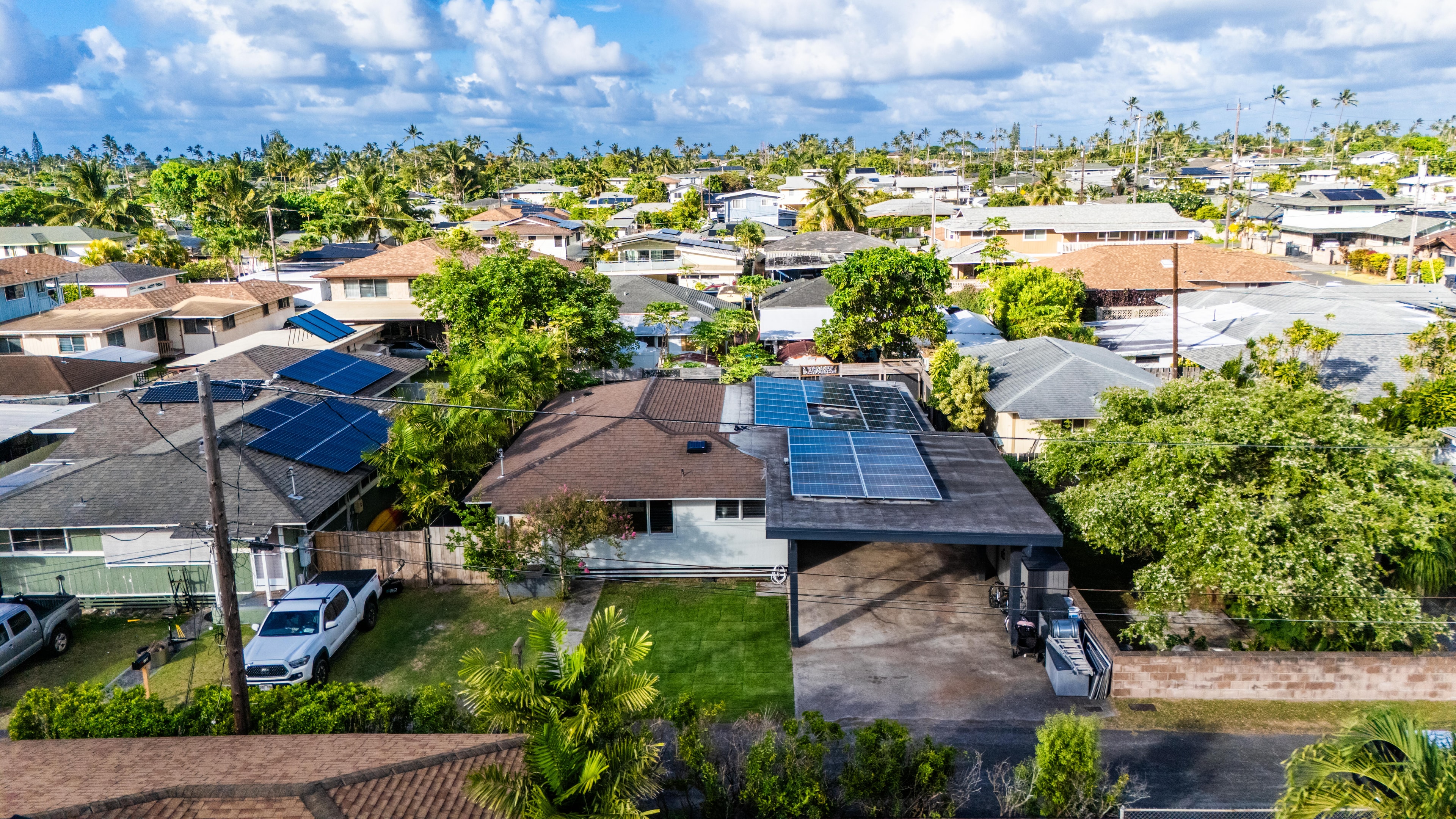 Aerial view of the home and surrounding Kailua neighborhood with solar panels visible on the roof
