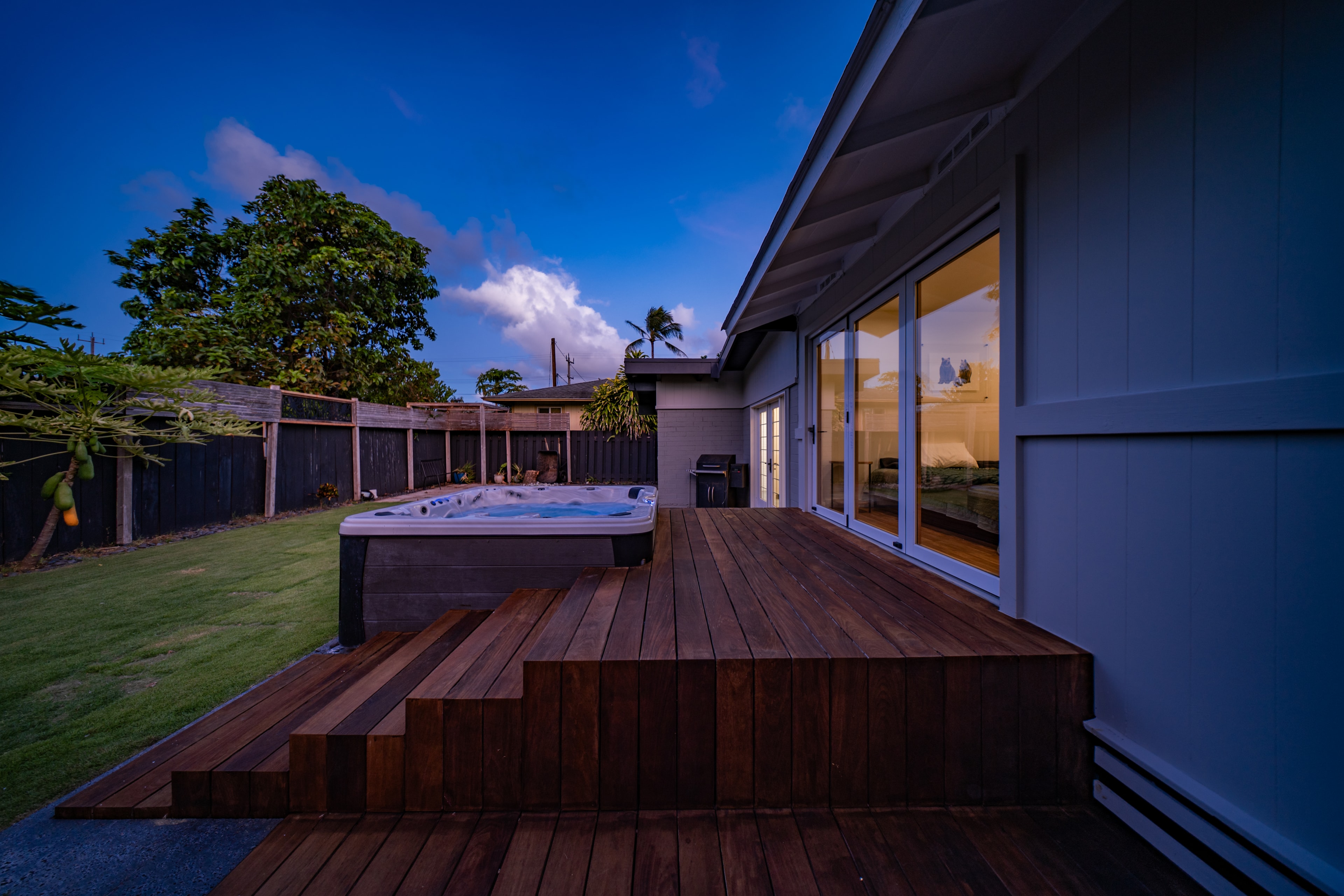 Backyard deck and hot tub at dusk with tropical sky
