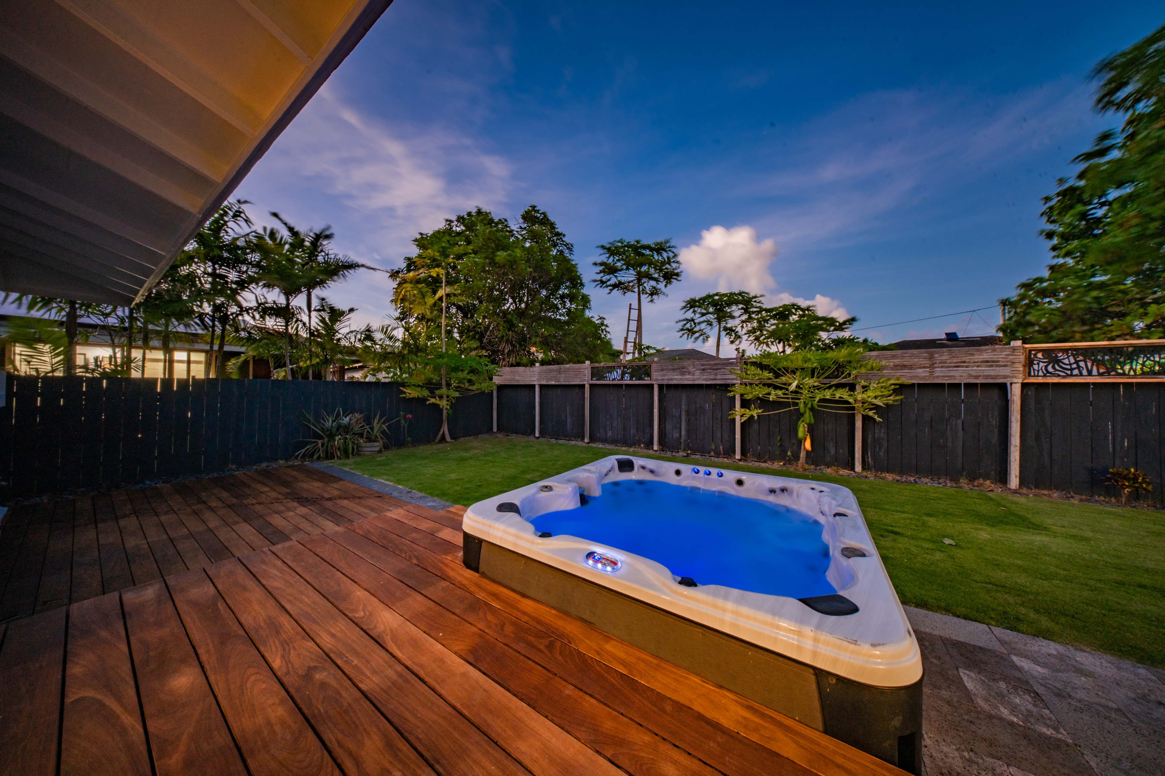 Evening view of the hot tub on the wood deck with tropical garden and deep blue sky