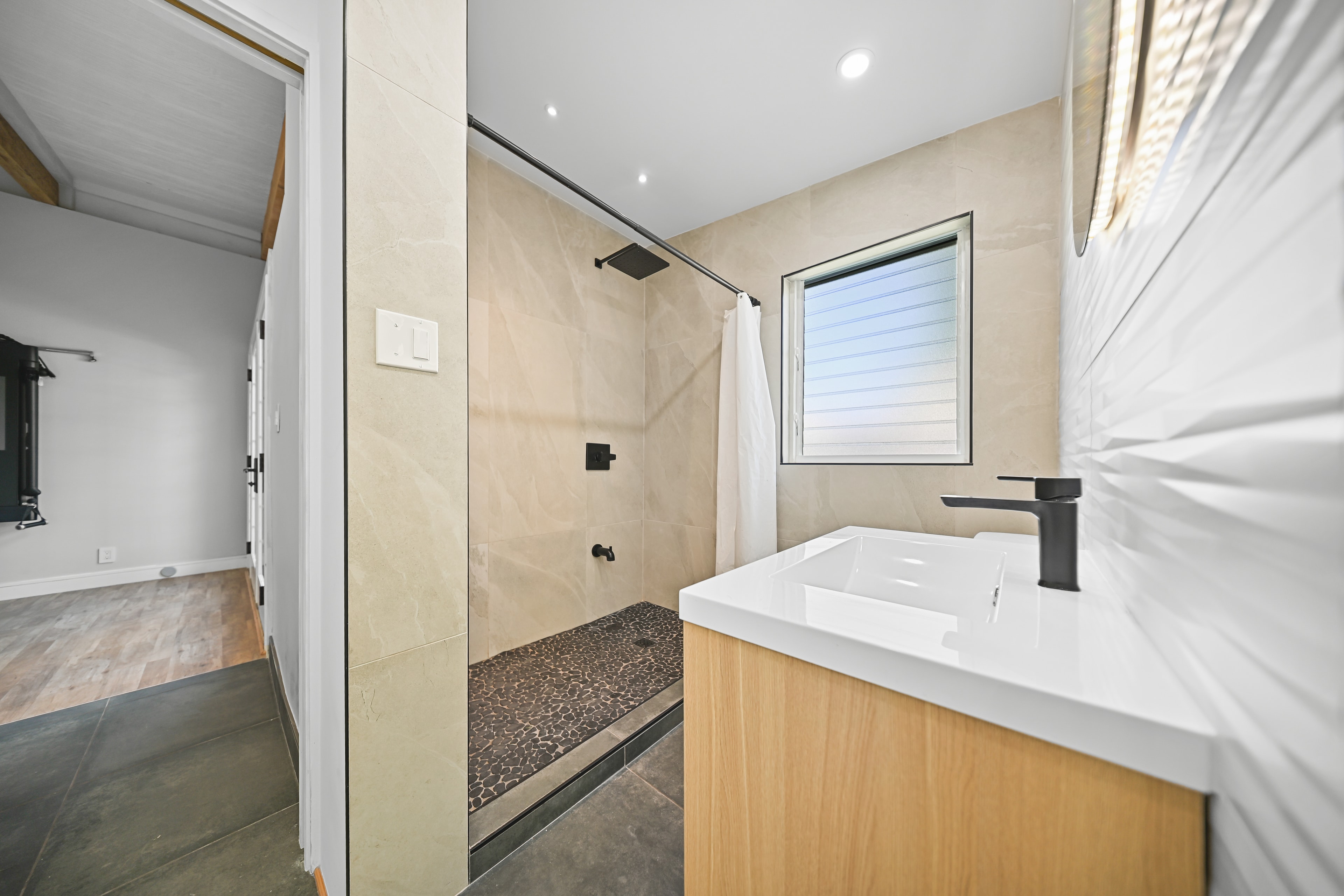 Walk-in shower with large-format tile, pebble floor, and black fixtures