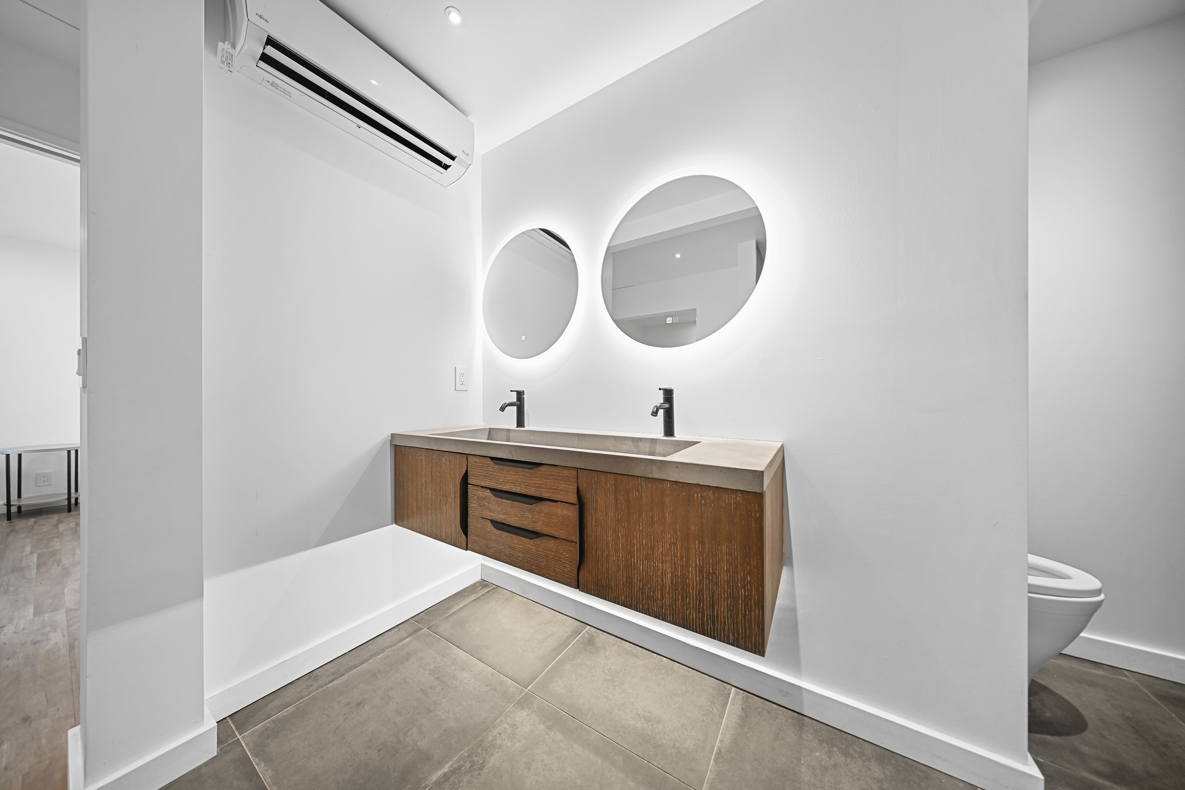 Primary bath vanity close-up — dual sinks, backlit mirrors
