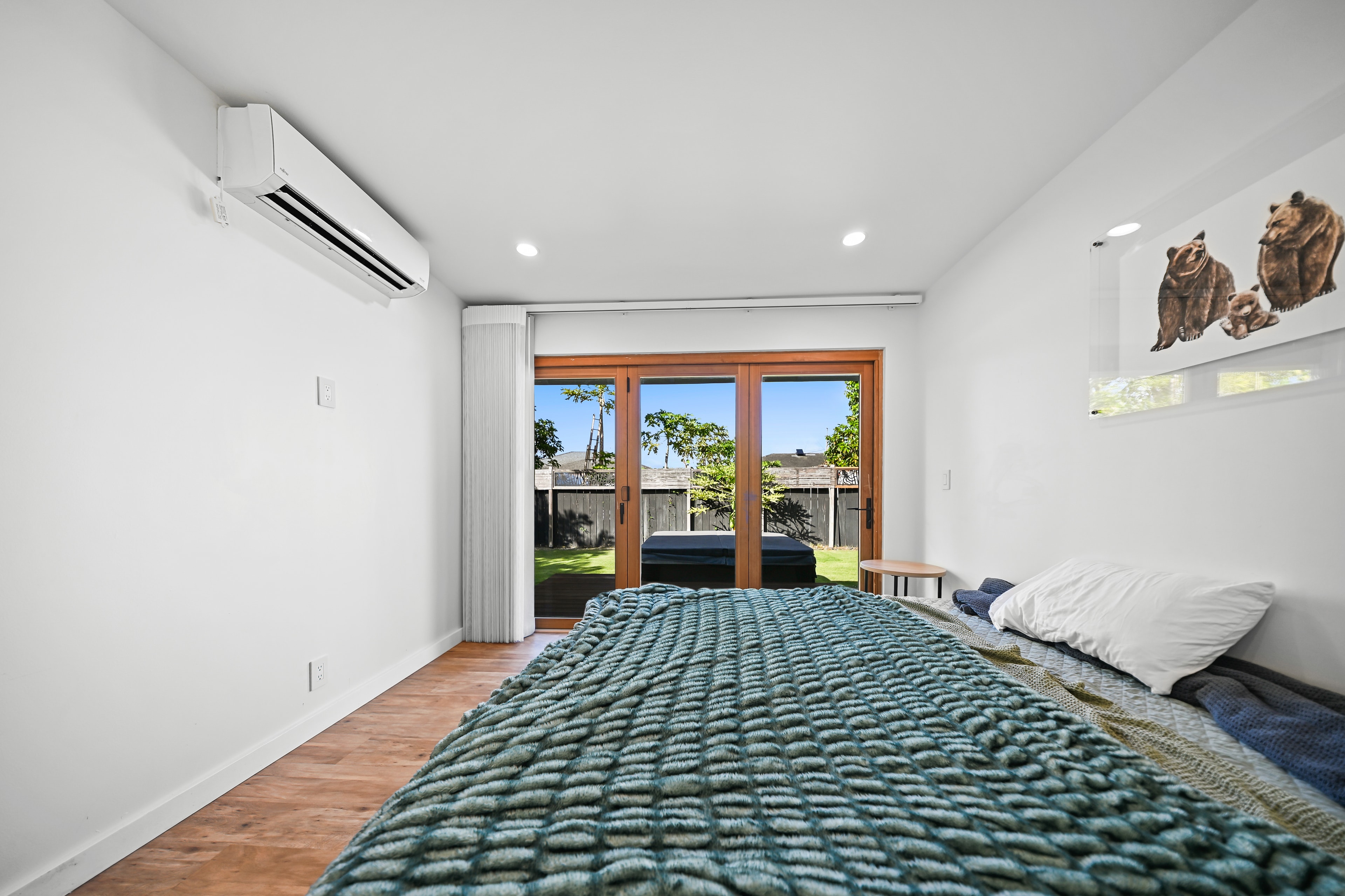 Bedroom with French doors opening to backyard, mini-split AC, and herringbone hardwood floors