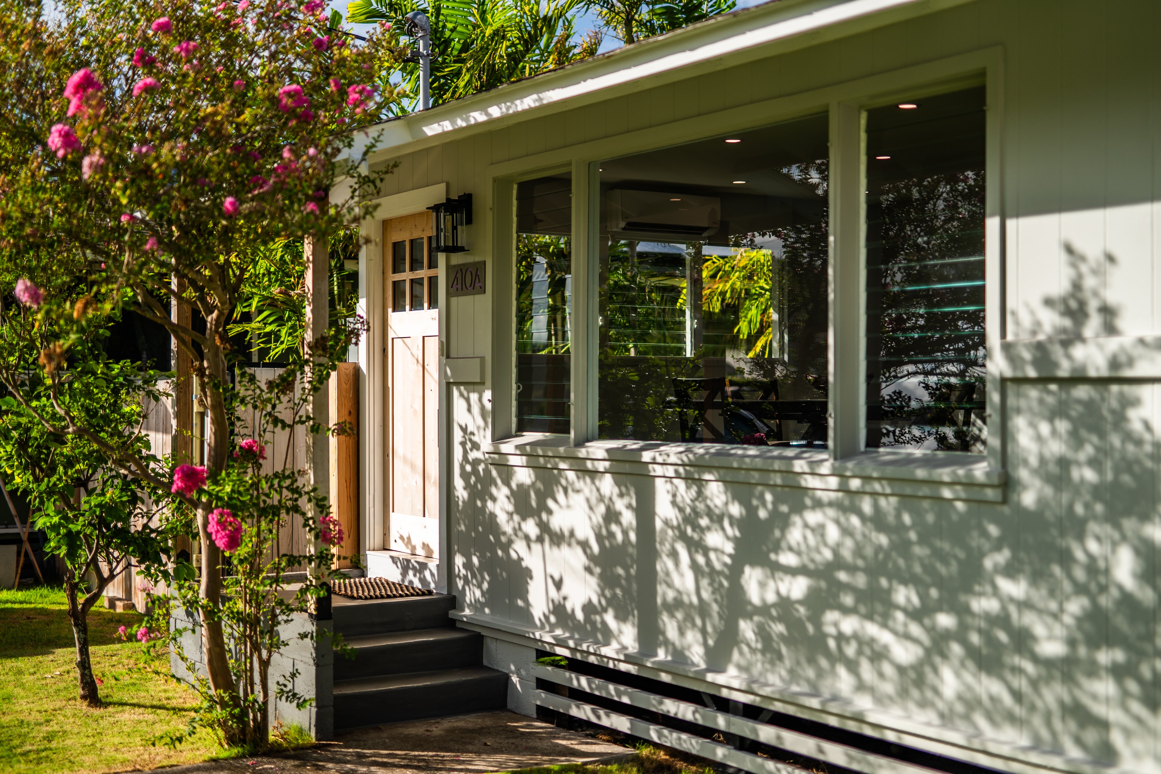 Front entry with 410A address sign, bougainvillea, and lush tropical landscaping