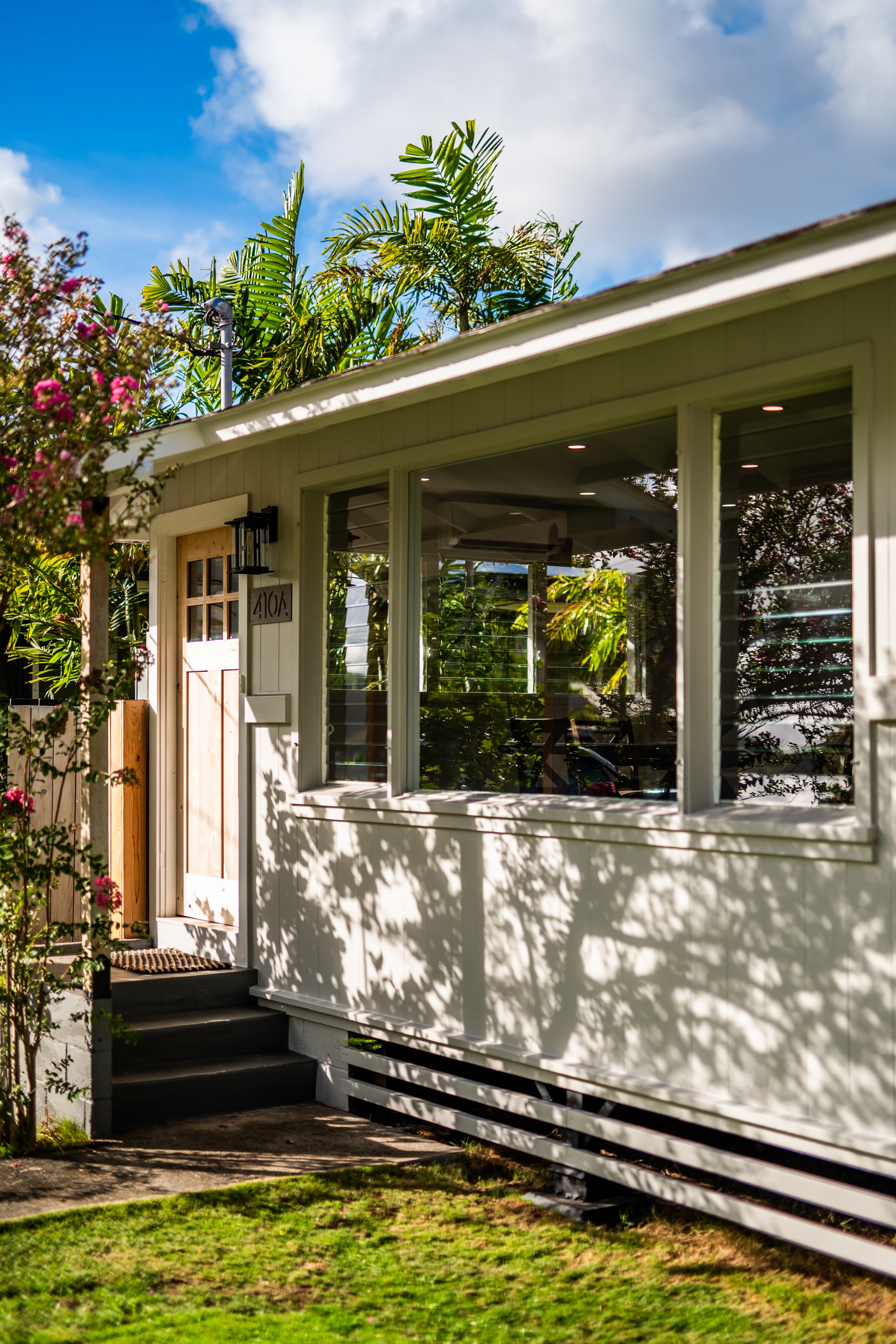 Front of home with dappled afternoon light through tropical trees
