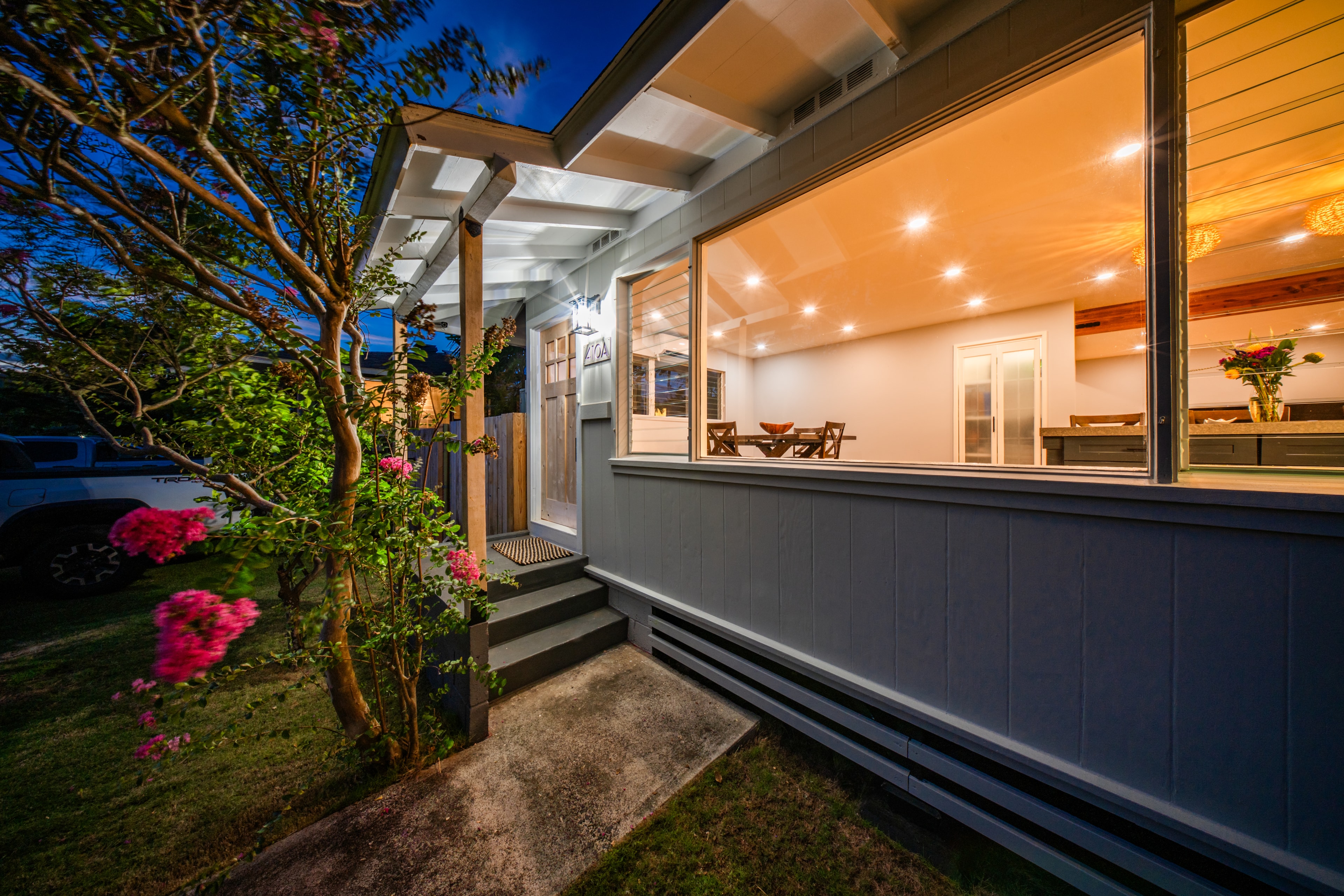 Front entry at dusk with warm interior lighting glowing through large windows