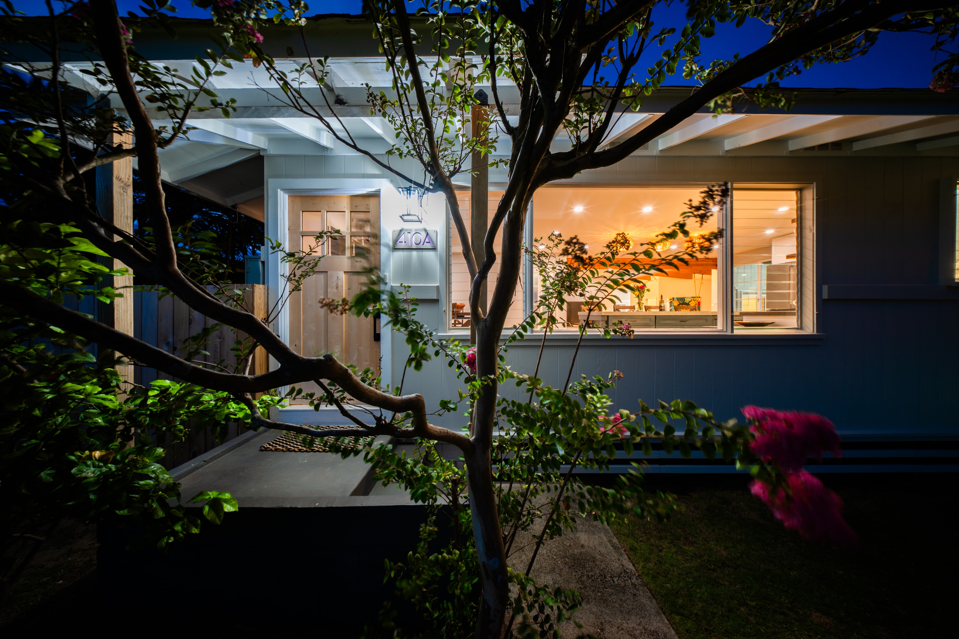 Evening view through the garden with the 410A sign lit up and kitchen visible inside