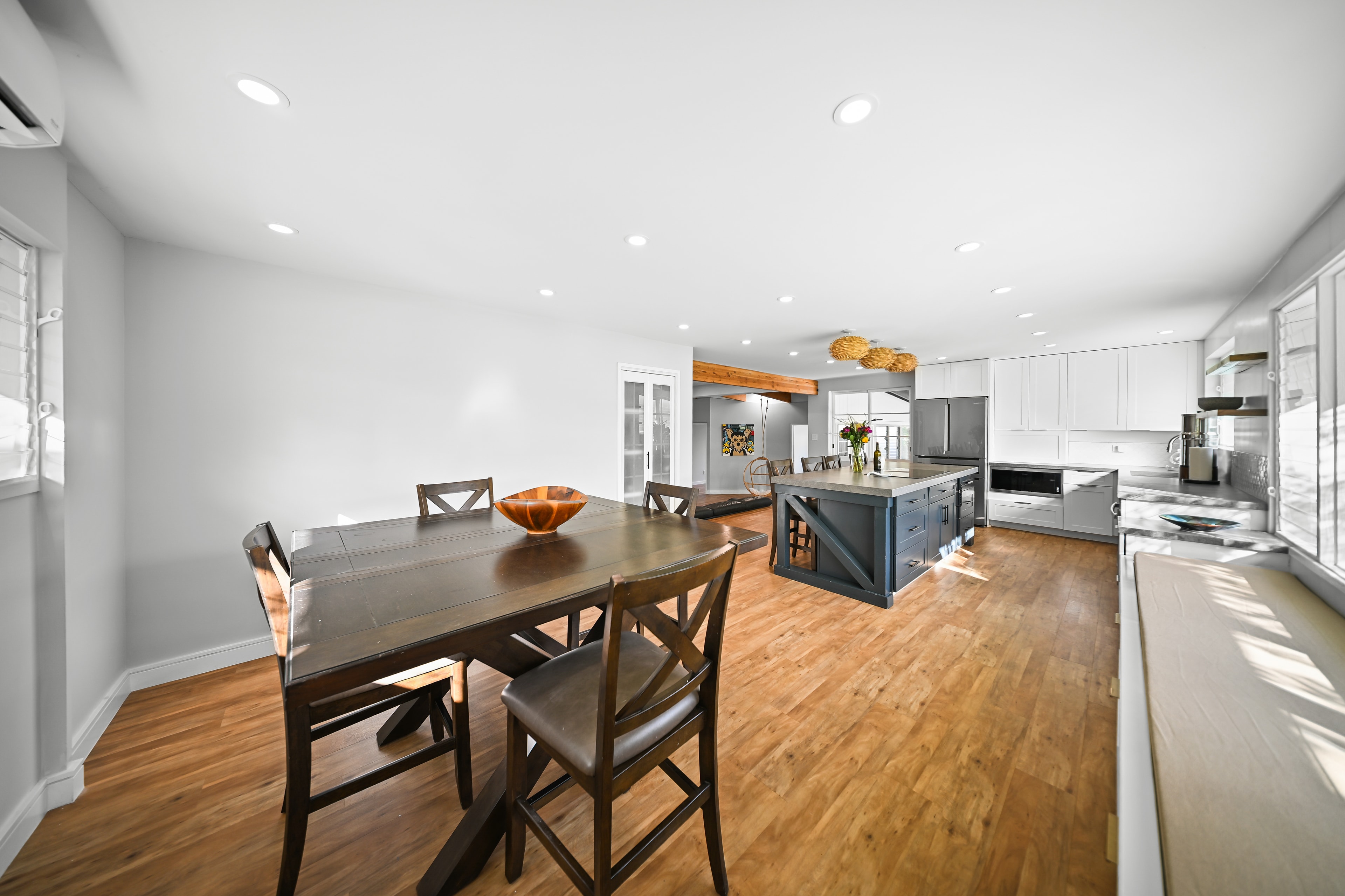 Kitchen and dining area with hardwood floors, dark island, and recessed lighting