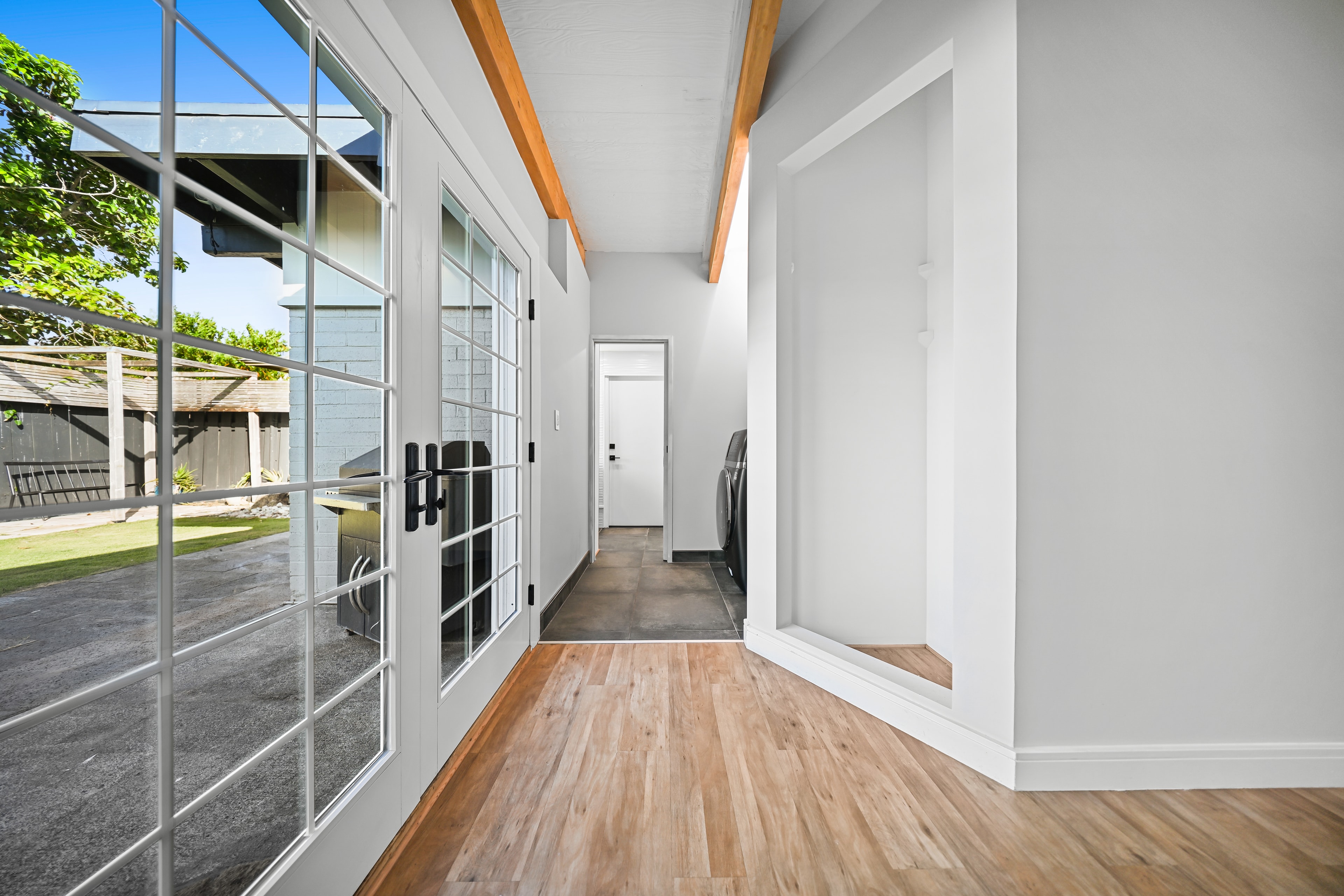 Mudroom hallway with French doors to yard, wood beams, and in-unit laundry