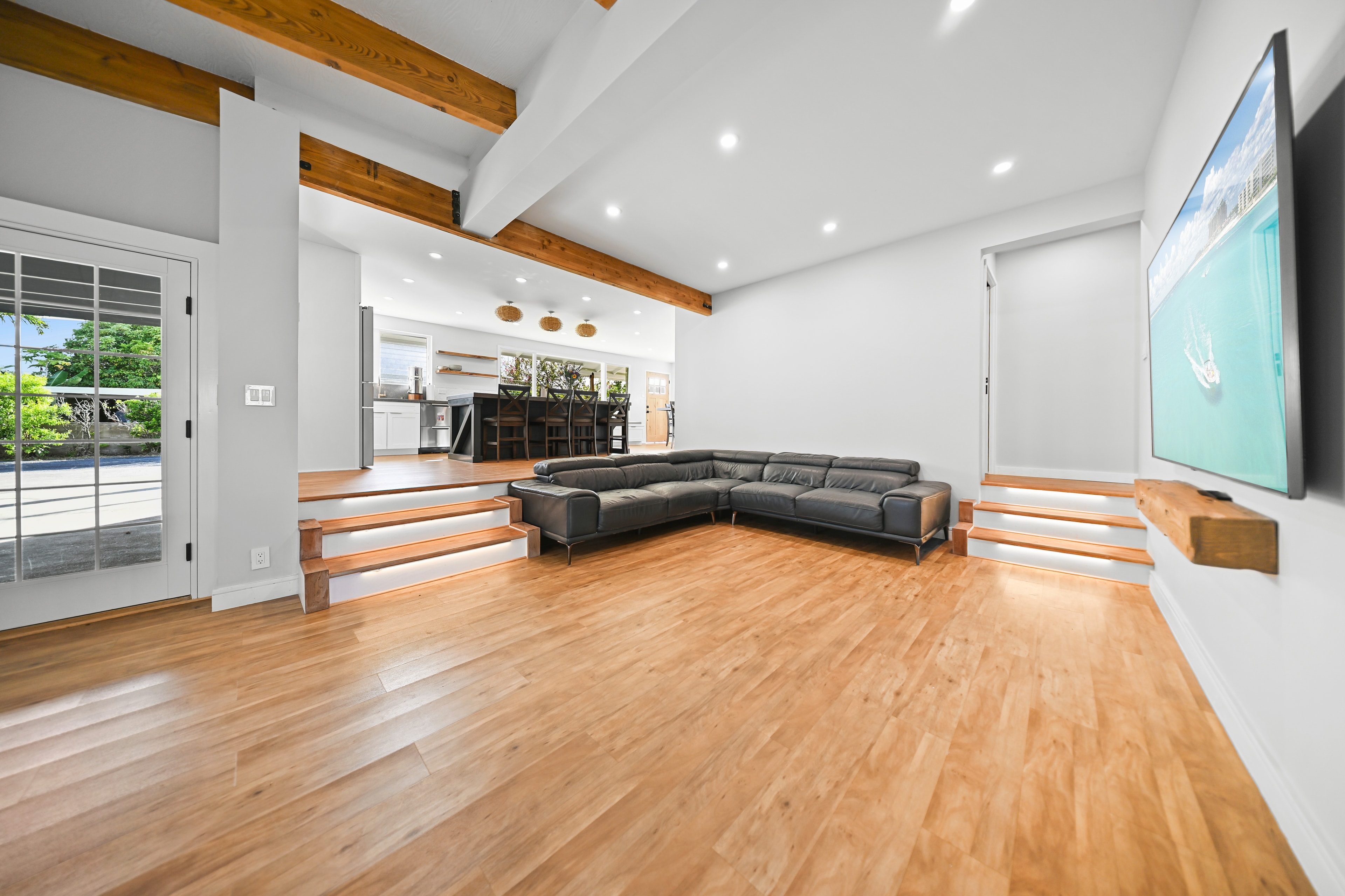 Wide shot showing the sunken living room layout, stepped platform, and kitchen beyond